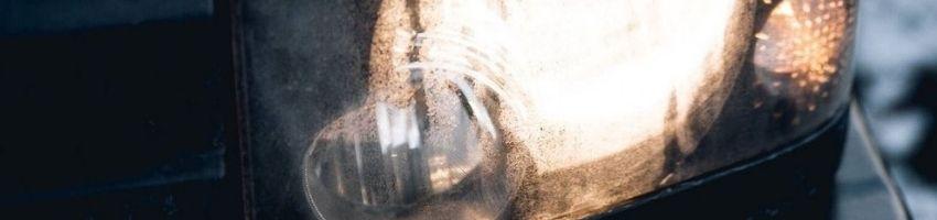 Old grey car turned on the car's lamp during winter