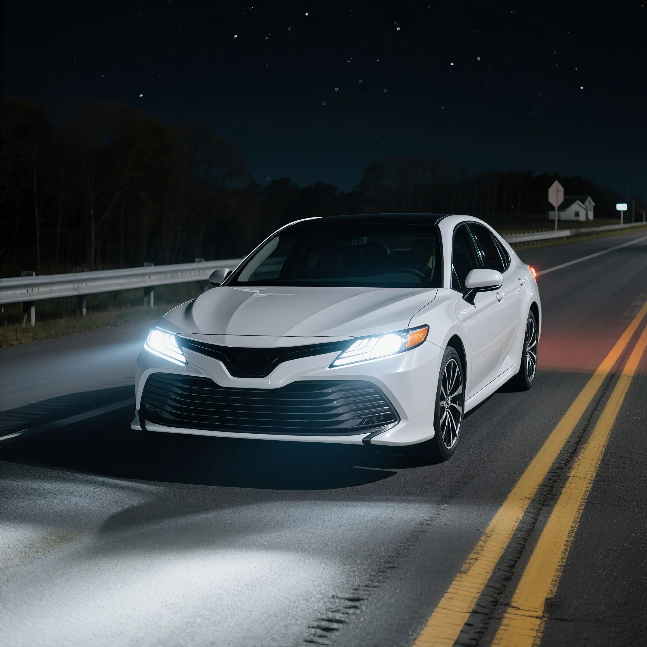 White car driving on a dark road at night with headlights on