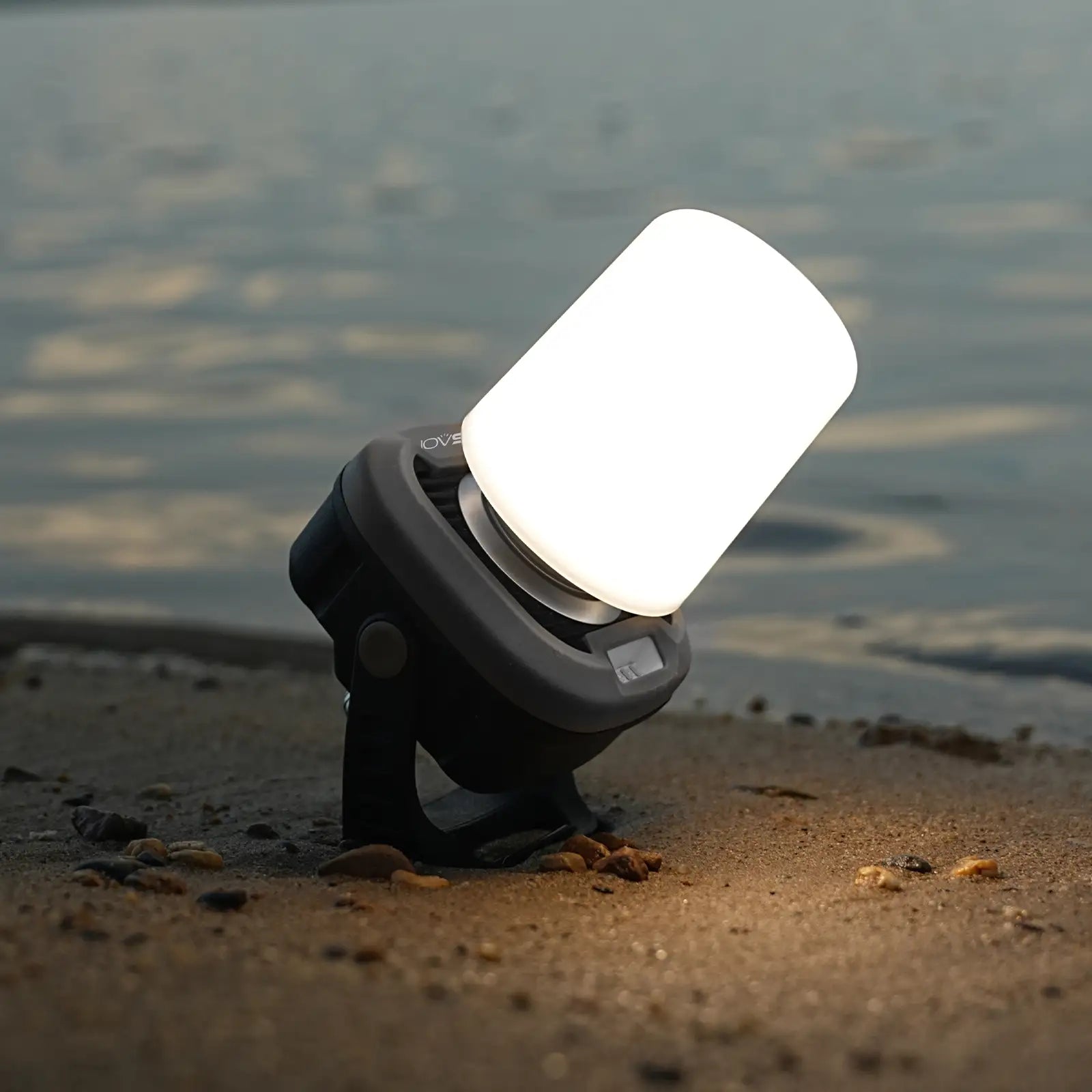 Portable light on a sandy beach with water in the background