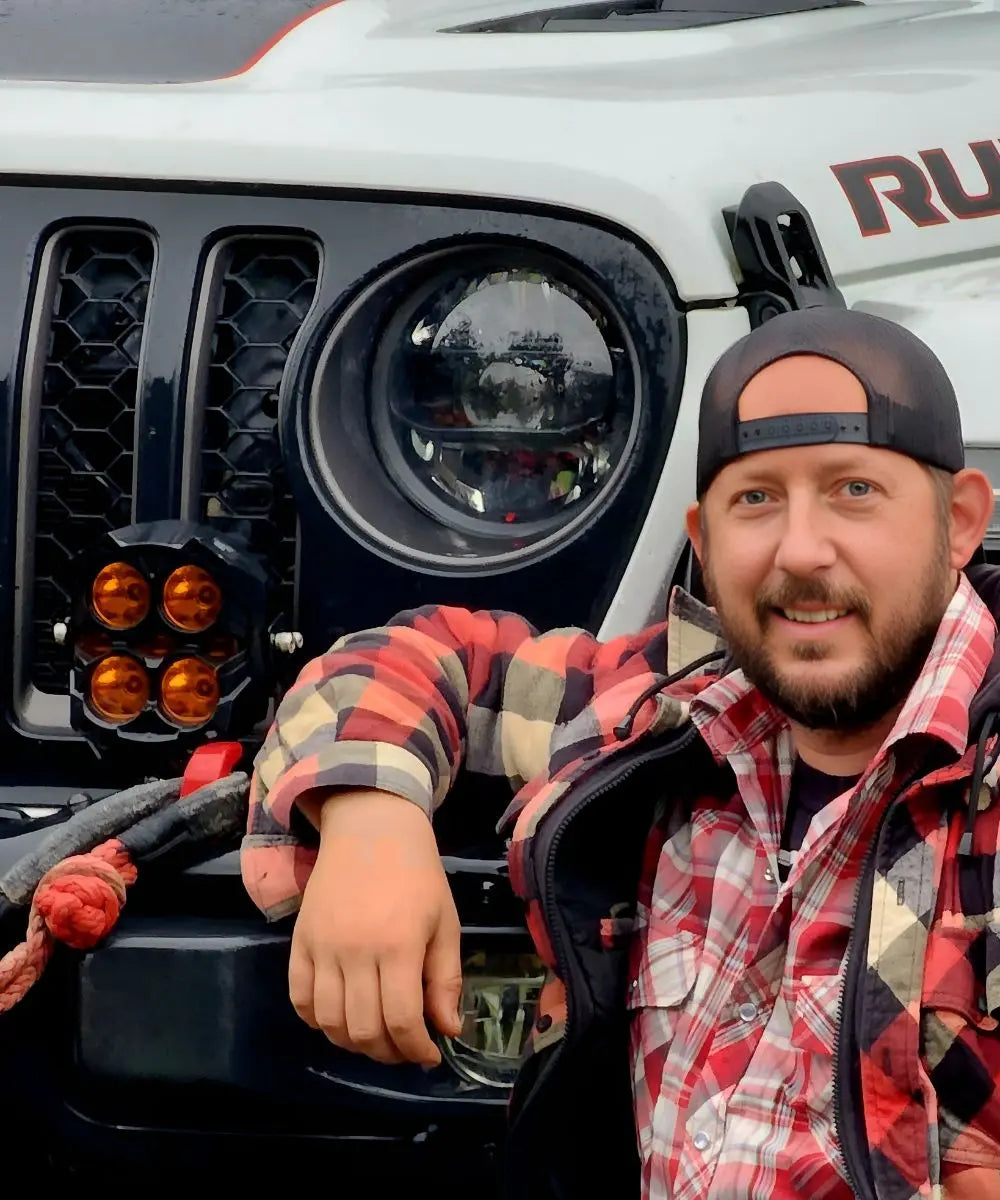 Man posing in front of a Jeep Rubicon with visible branding