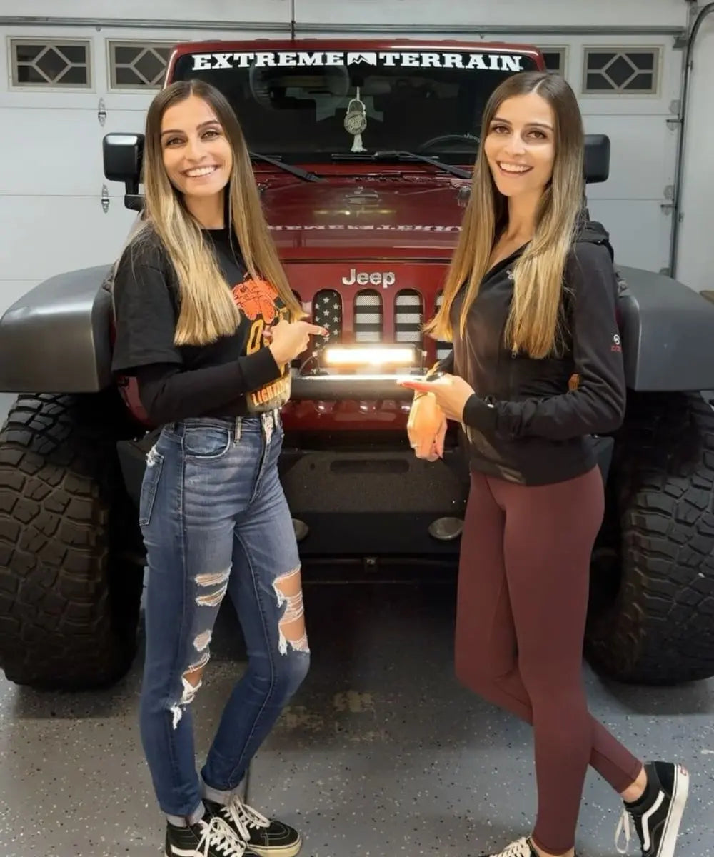 Two women standing in front of a red Jeep with 'Extreme Terrain' on the windshield.