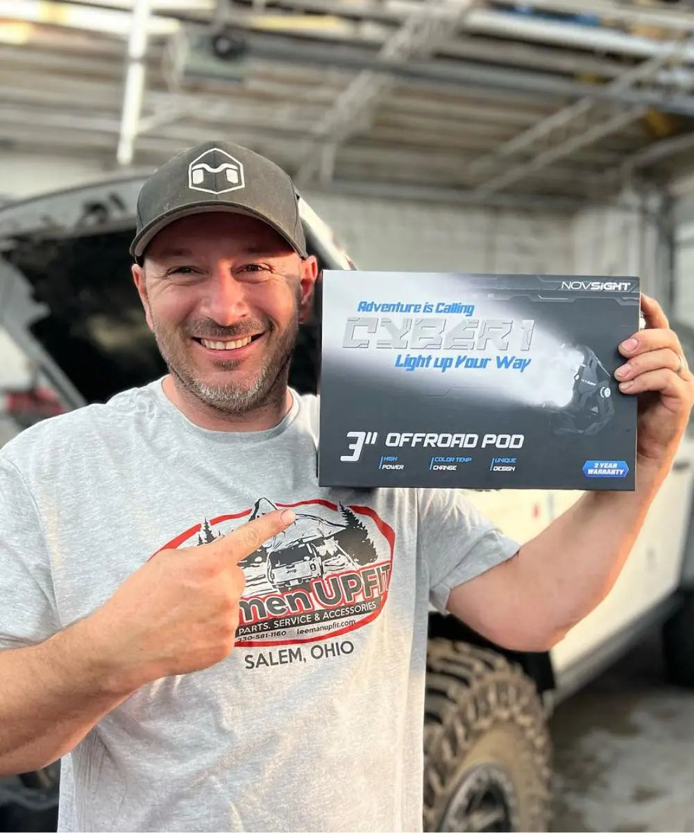 Man holding a box of Novolight off-road pod in front of a vehicle