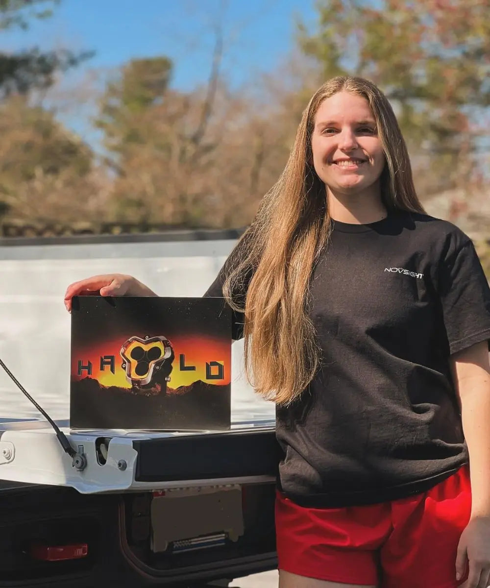 Person holding a laptop with a novsight halo pod light in front of a vehicle